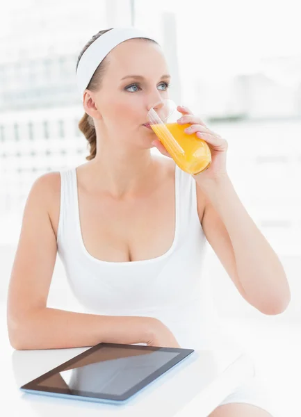 Pensive pretty sportswoman drinking orange juice — Stock Photo, Image