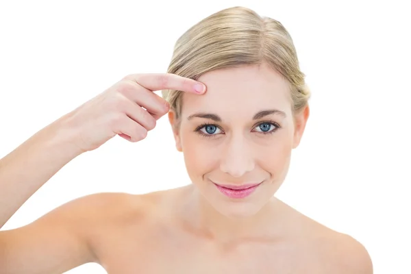 Zufriedene junge blonde Frau zeigt mit dem Finger auf ihre Stirn — Stockfoto