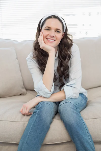 居心地の良いソファの上に座っているカジュアルな女性の笑みを浮かべてください。 — ストック写真