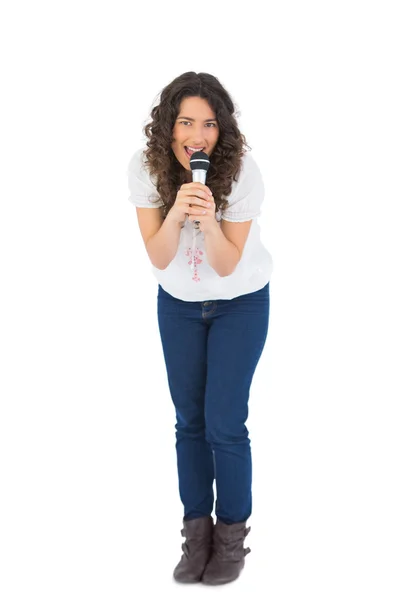 Happy pretty brunette singing with her microphone — Stock Photo, Image