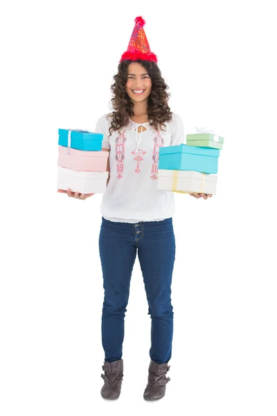 Smiling casual brunette wearing party hat holding presents — Stock Photo, Image
