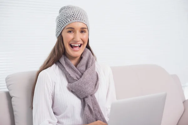 Morena feliz com chapéu de inverno em usar seu laptop — Fotografia de Stock