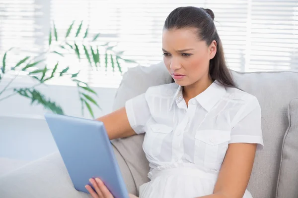 Serious cute woman using tablet sitting on cosy sofa — Stock Photo, Image