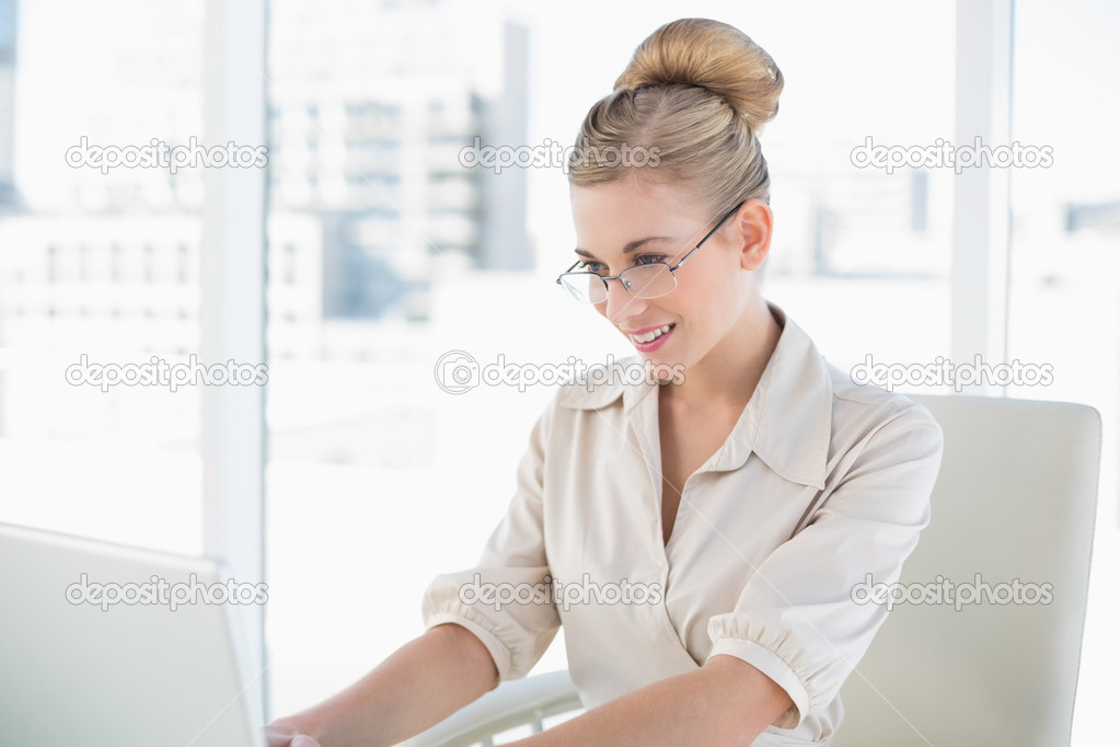 Focused young blonde businesswoman using a laptop