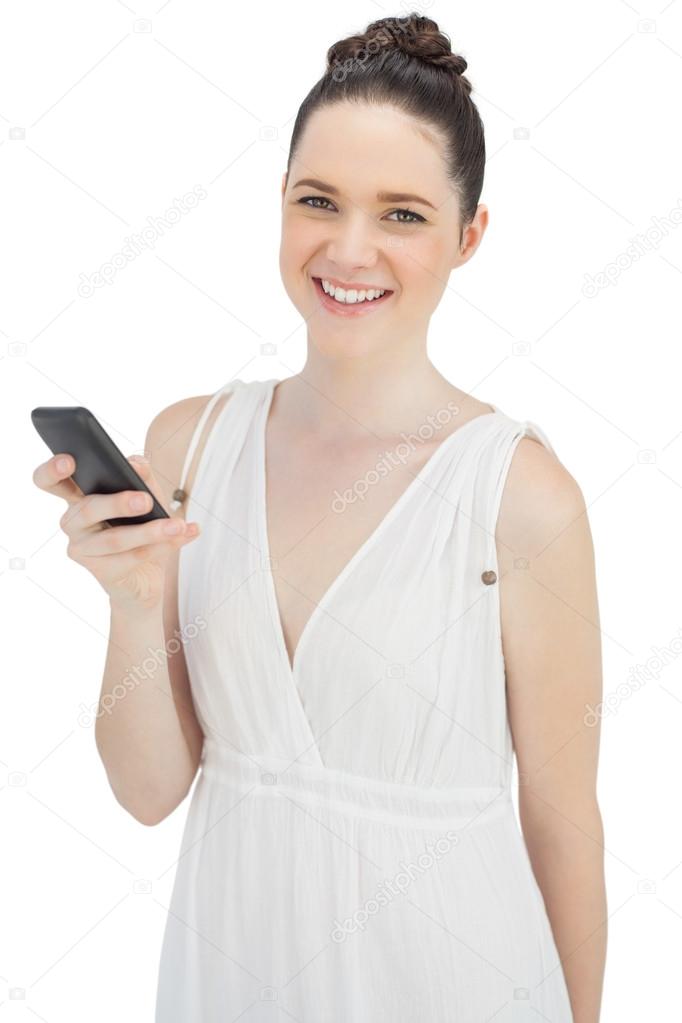 Cheerful pretty model in white dress sending text message