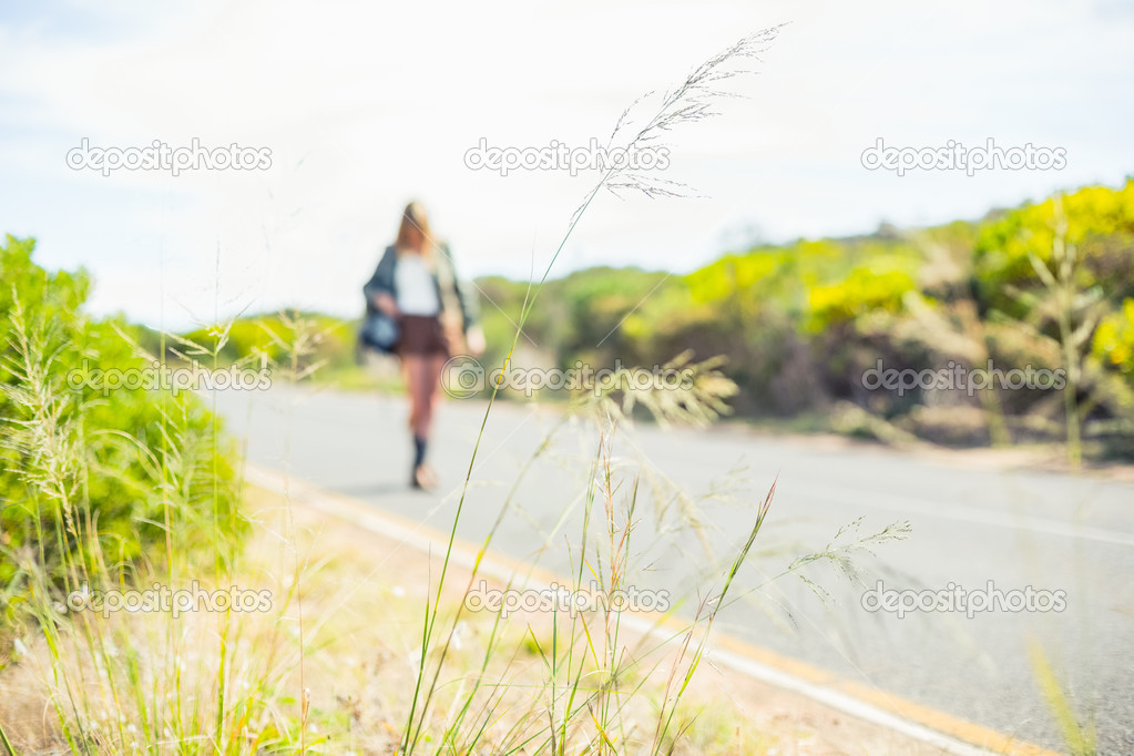 Focus on straw with blonde walking on the road on background