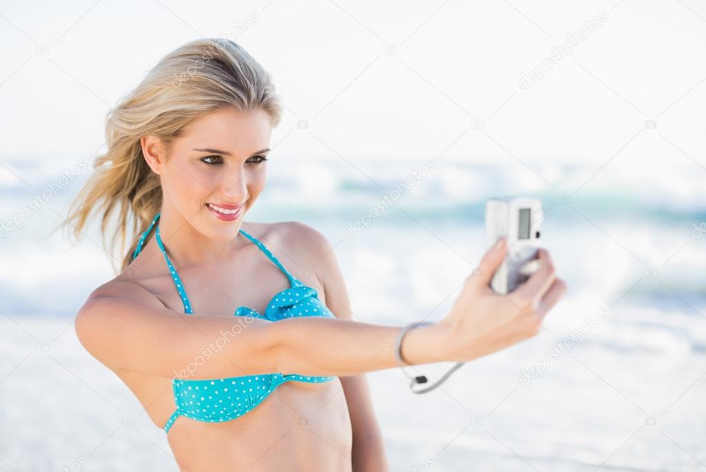 Cheerful sexy blonde in bikini taking a self picture