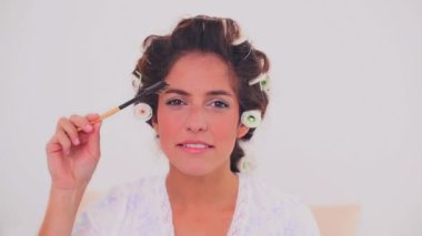 kaşlarını fırçalama saç curlers içinde gülümseyen kadın