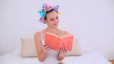 Genç model saç Silindirler yatağının üzerine bir kitap okuma