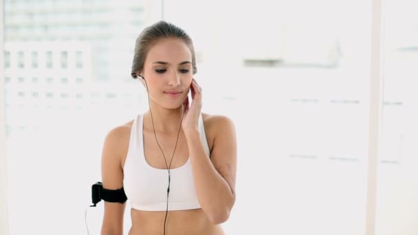 Genç kadın müzik aygıtı bir kol bandı ve değişen şarkıyı dinlerken uygun — Stok video
