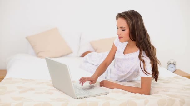 Young woman using her laptop lying on her bed — Stock Video