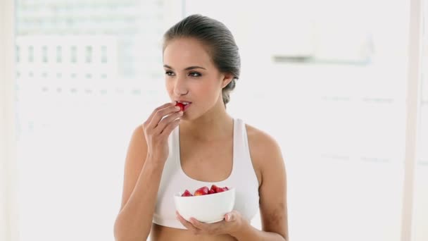 Ajuste mujer joven comiendo un tazón de fresas — Vídeos de Stock