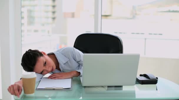 Exhausted businesswoman waking up from a nap at her desk — Stock Video