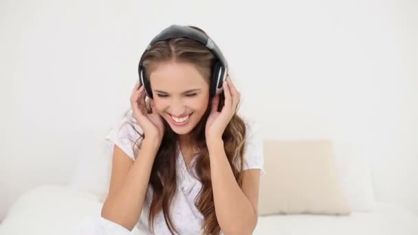 Jovem mulher ouvindo música e dançando em sua cama — Vídeo de Stock