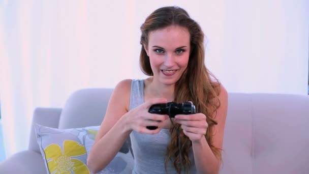 Modelo sonriente jugando videojuegos en el sofá — Vídeos de Stock