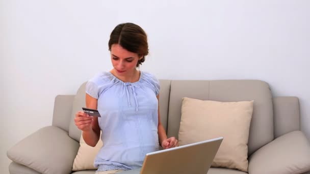 Pregnant woman using her laptop for shopping online on the couch — Stock Video