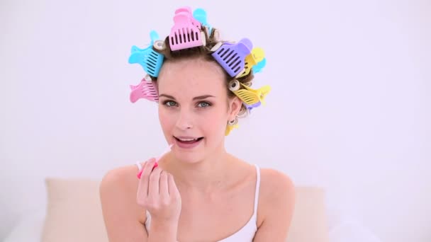 Молодая модель в роликах для волос с блеском для губ — стоковое видео