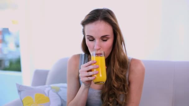 Modelo feliz bebiendo jugo de naranja en el sofá — Vídeos de Stock