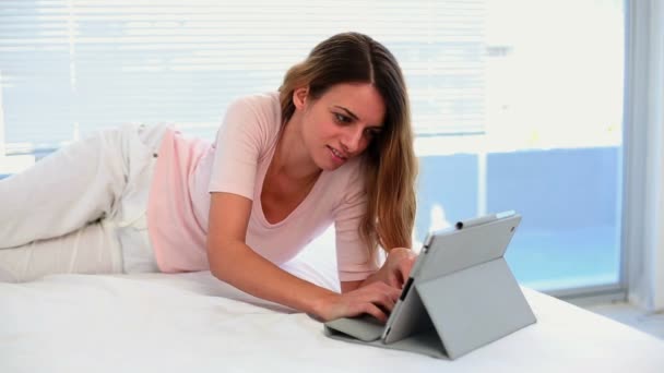 Hübsche Frau liegt und benutzt ihren Tablet-PC — Stockvideo