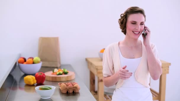 Pretty model standing in kitchen talking on the phone — Stock Video