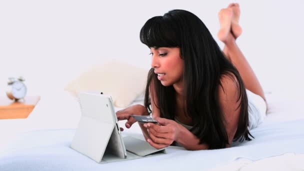 Belle femme couchée sur son lit en utilisant sa tablette PC pour faire du shopping en ligne — Video