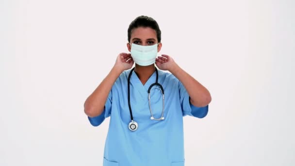 Lachende mooie verpleegster zetten een chirurgische masker — Stockvideo