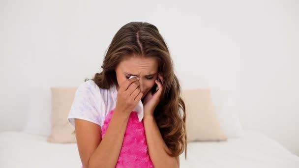 Young woman being dumped over the phone on her bed holding a heart cushion — Stock Video