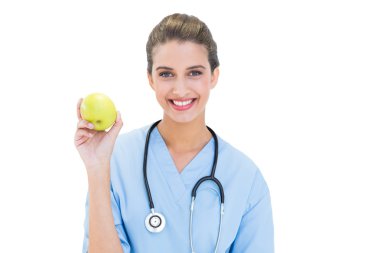 Yeşil elma tutan mavi içerik hemşire scrubs