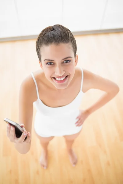Donna in abbigliamento sportivo bianco con in mano un telefono cellulare — Foto Stock