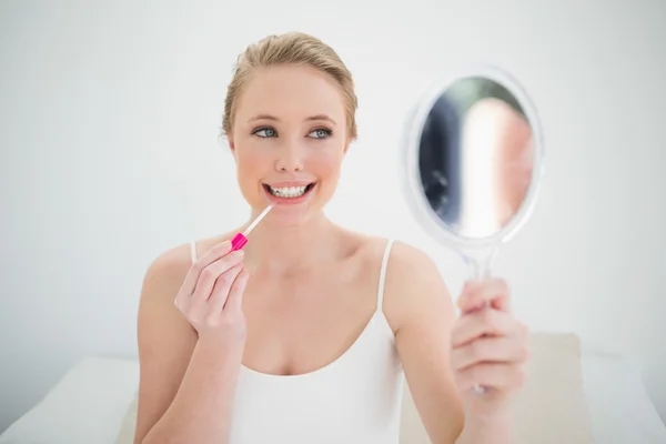 Natuurlijke gelukkig blonde spiegel te houden en toe te passen lipgloss — Stockfoto