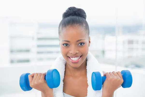 Fit woman with towel around her neck working out with dumbbell — Stock Photo, Image