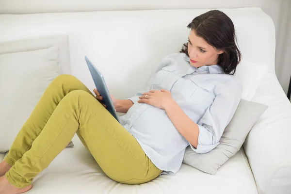 Thinking pregnant woman using a tablet pc — Stock Photo, Image