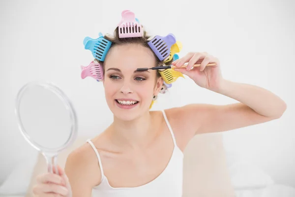 Mujer atractiva en rulos de pelo aplicando rímel —  Fotos de Stock