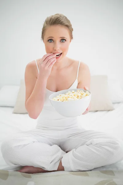 Natuurlijke vrolijke blonde eten popcorn op bed — Stockfoto