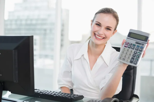 Kalkulator wyświetlone szczęśliwa kobieta siedzi przy biurku — Zdjęcie stockowe