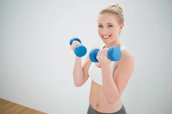 Happy sporty blonde holding dumbbells — Stock Photo, Image