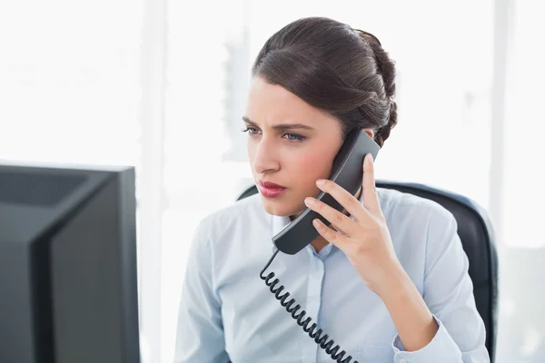 Stern businesswoman answering the telephone — Stock Photo, Image