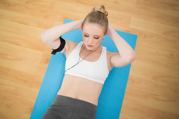 Aantrekkelijke sportieve blonde luisteren naar muziek en uitoefening van — Stockfoto