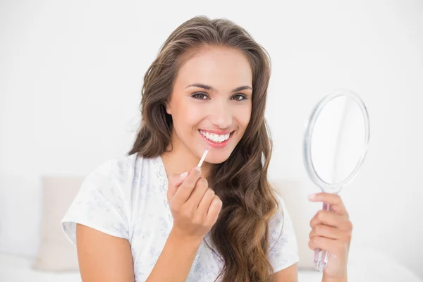 Morena aplicando brilho labial e espelho de retenção — Fotografia de Stock