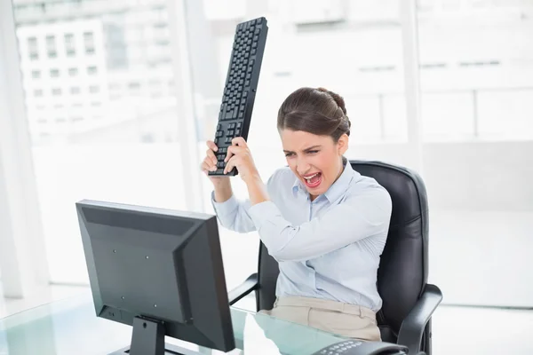 Furiosa empresária jogando seu teclado em seu computador — Fotografia de Stock