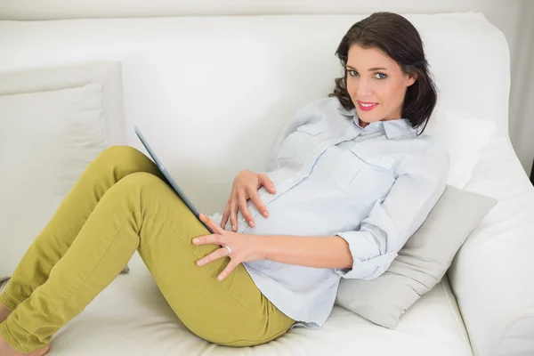 Vreedzame zwangere bruin donkerharige vrouw met behulp van een tablet pc — Stockfoto