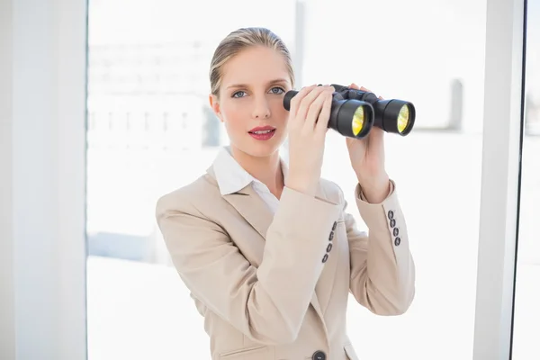 Peaceful blonde businesswoman holding binoculars — Stock Photo, Image