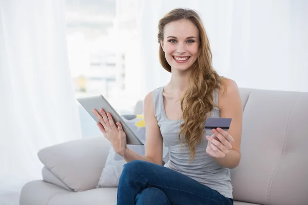 Jovem feliz sentada no sofá usando tablet — Fotografia de Stock