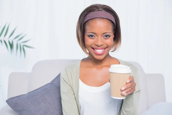 Smiling woman sitting on sofa holding coffee — Stock Photo, Image