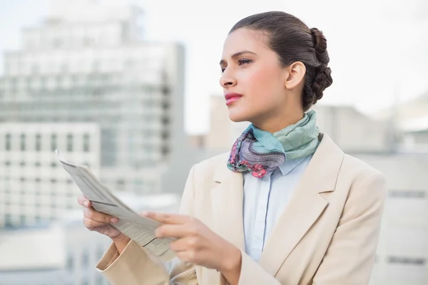 Thinking businesswoman holding a newspaper — Stock Photo, Image