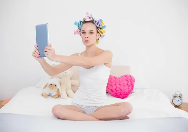 Femme en bigoudis de cheveux prenant une photo d'elle-même avec une tablette — Photo