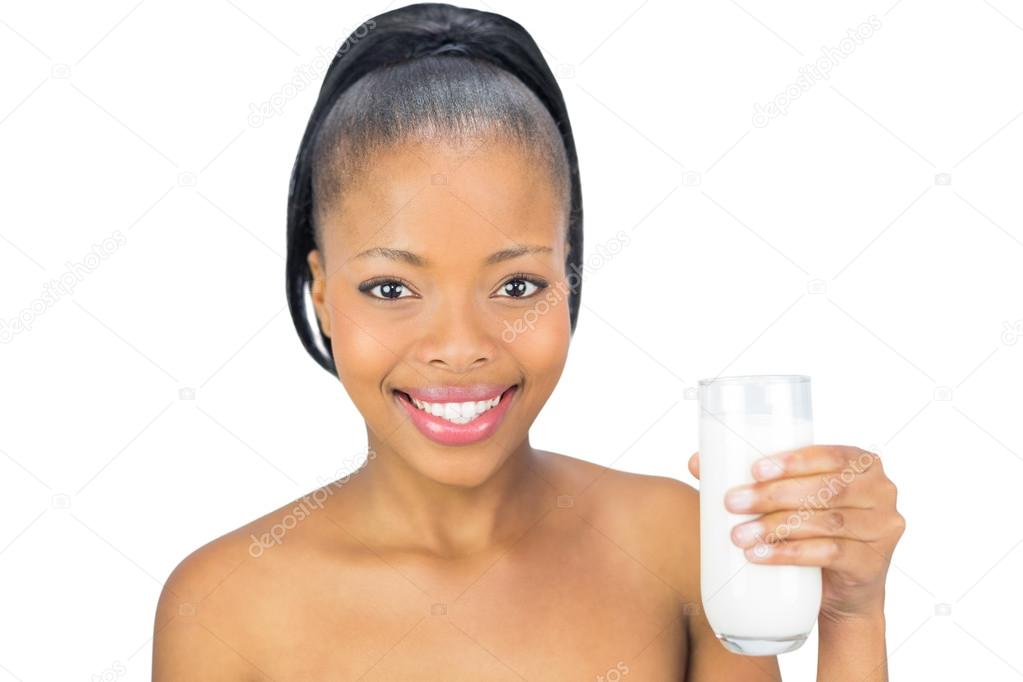 Happy woman holding glass of milk and looking at camera