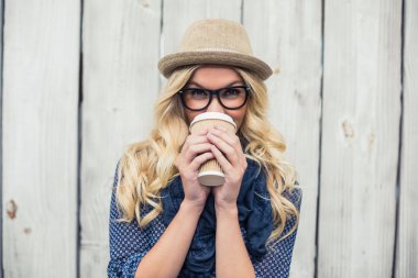 Smiling fashionable blonde drinking coffee outdoors