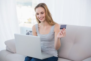 jonge vrouw zittend op de Bank met behulp van laptop voor online winkelen