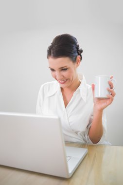 kahve holding dizüstü bilgisayar üzerinde çalışan iş kadını gülümseyen